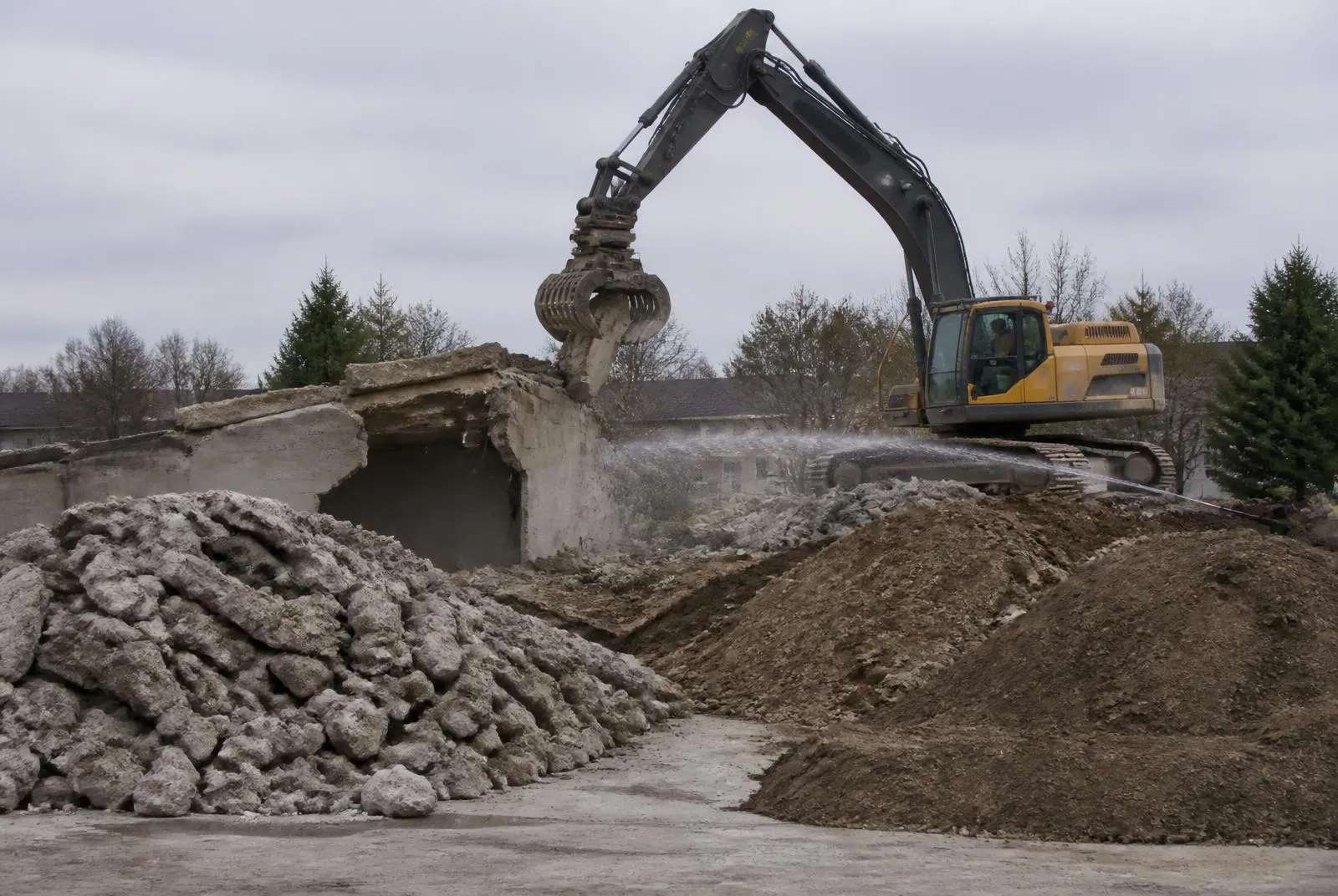 Bagger mit Sortiergreifer beim kontrollierten Rückbau eines Betonbauteils, Material getrennt gelagert